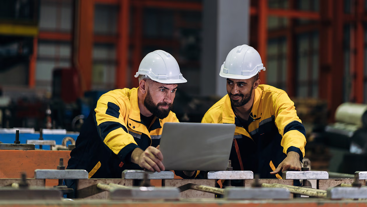 Two workers viewing safety videos on a computer.